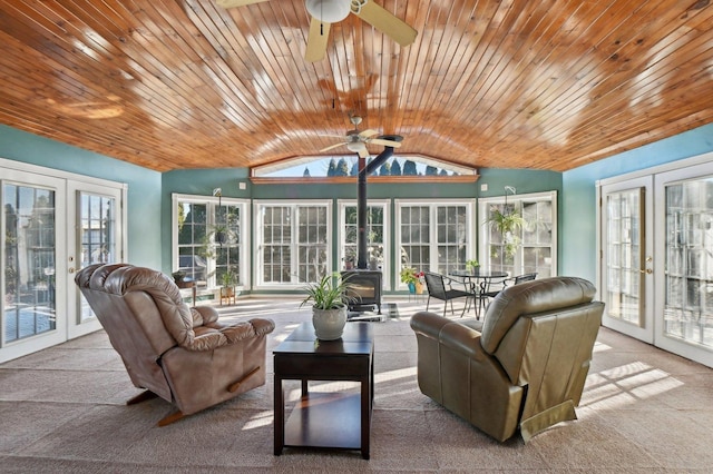 sunroom / solarium with french doors, a wood stove, lofted ceiling, and carpet flooring