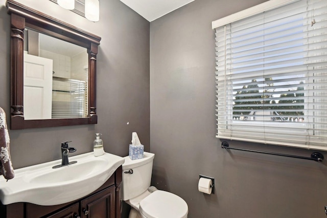 bathroom with toilet, a shower with door, and vanity