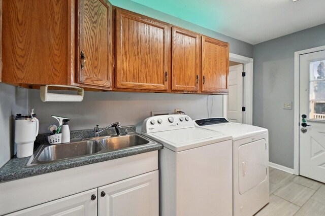 laundry room featuring baseboards, a sink, cabinet space, and washing machine and dryer
