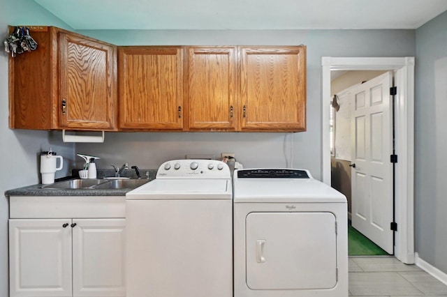 washroom with cabinet space, baseboards, a sink, and washer and clothes dryer