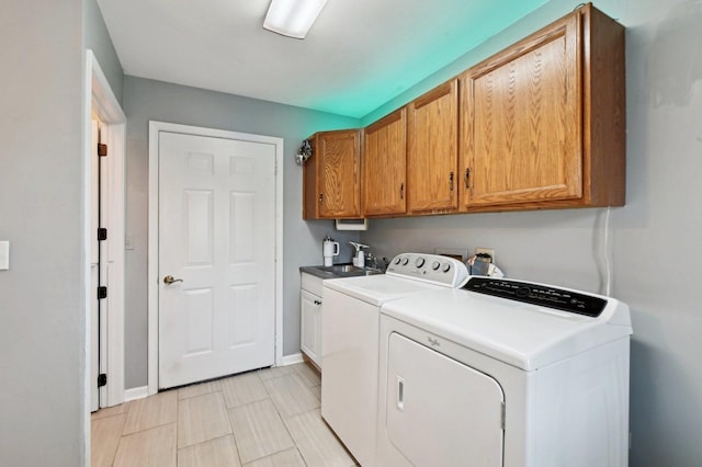 washroom with a sink, baseboards, independent washer and dryer, and cabinet space