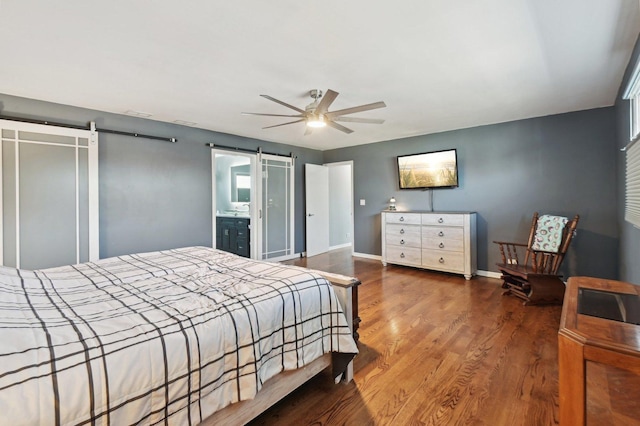 bedroom with baseboards, a ceiling fan, a barn door, and wood finished floors