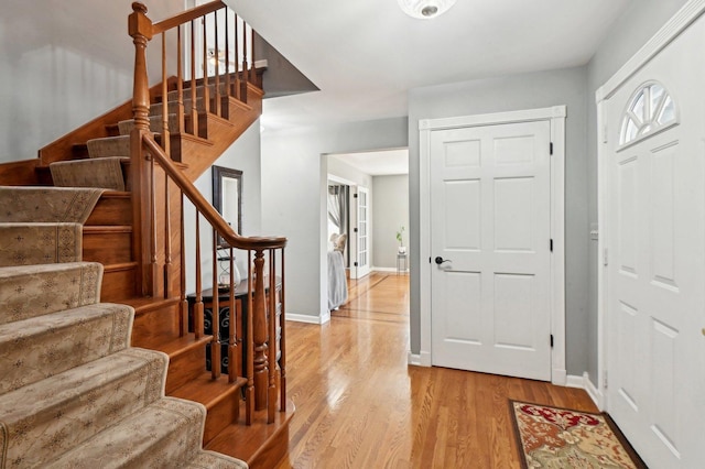 entrance foyer featuring stairs, baseboards, and light wood-style flooring