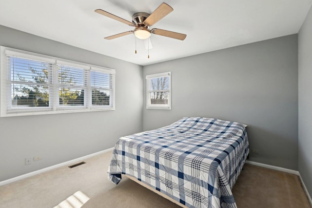 carpeted bedroom featuring baseboards, a ceiling fan, and visible vents