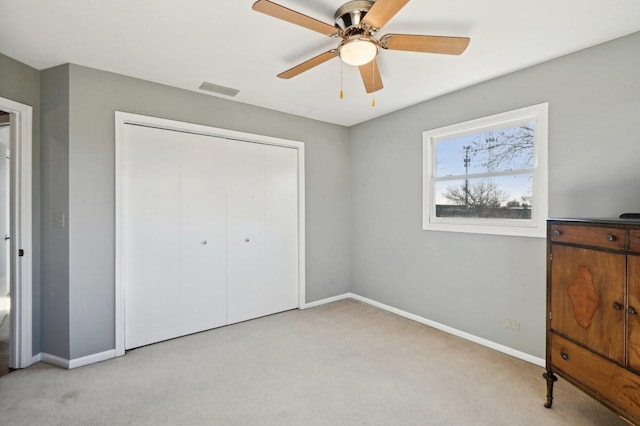 unfurnished bedroom featuring a ceiling fan, baseboards, light carpet, and a closet