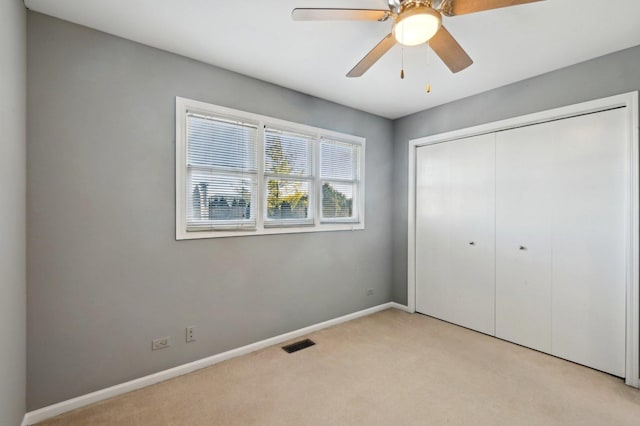 unfurnished bedroom with carpet flooring, ceiling fan, baseboards, visible vents, and a closet