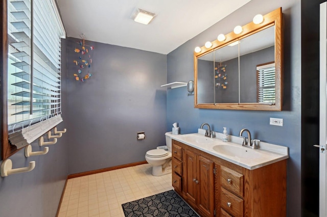 bathroom with toilet, a healthy amount of sunlight, and a sink
