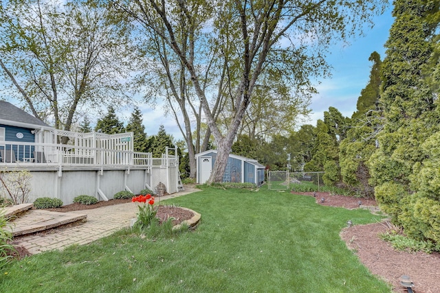 view of yard with fence, a storage unit, a wooden deck, an outbuilding, and a patio
