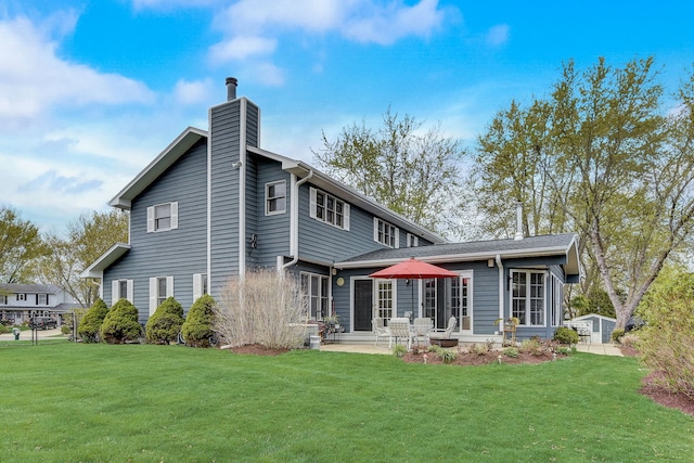back of property featuring a lawn, a patio, and a chimney