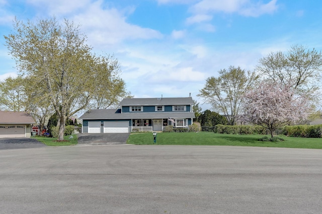 view of front of home featuring covered porch, an attached garage, driveway, and a front lawn