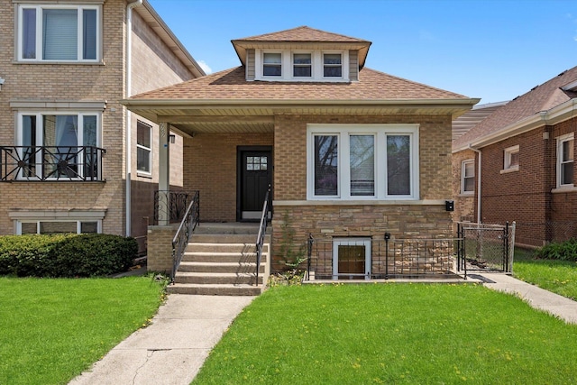 view of front of house featuring a porch, a shingled roof, and a front yard