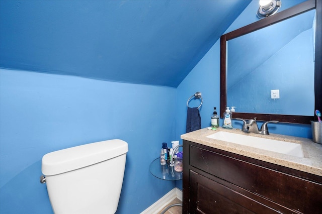 bathroom featuring vanity, baseboards, vaulted ceiling, and toilet