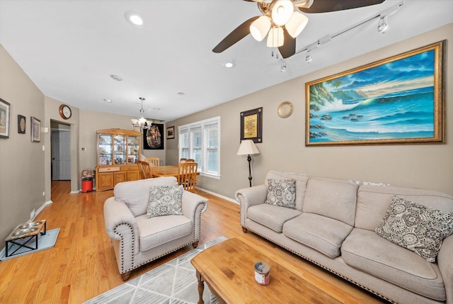 living room with recessed lighting, baseboards, ceiling fan with notable chandelier, and light wood-type flooring