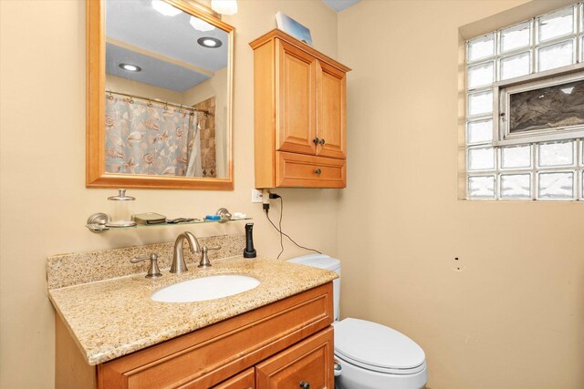 full bath with toilet, a shower with curtain, plenty of natural light, and vanity