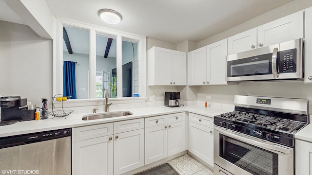 kitchen with a sink, light countertops, white cabinets, and stainless steel appliances
