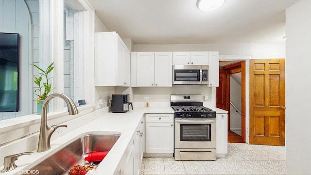 kitchen with light countertops, white cabinetry, appliances with stainless steel finishes, and a sink