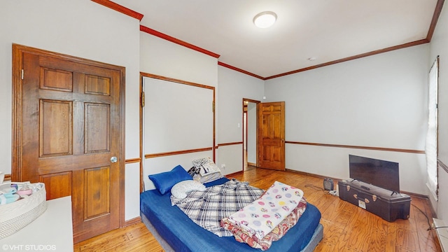 bedroom with baseboards, ornamental molding, wood finished floors, and a closet
