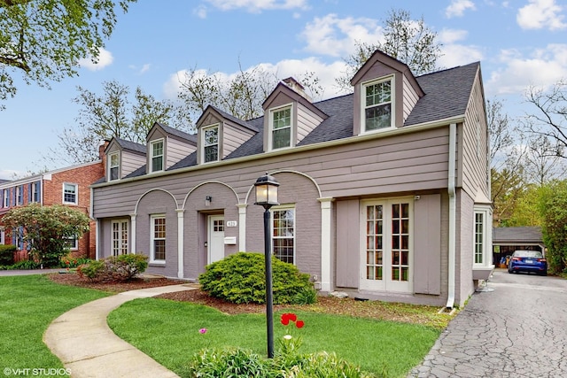 cape cod home with brick siding, a shingled roof, and a front yard