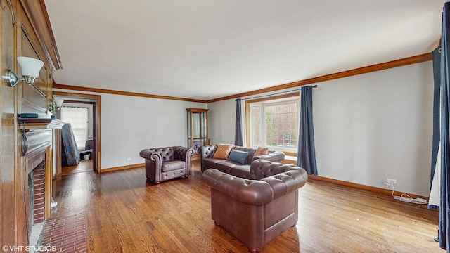 living area featuring crown molding, baseboards, wood finished floors, and a fireplace