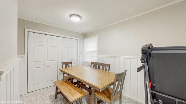 dining area featuring crown molding, wainscoting, and a decorative wall