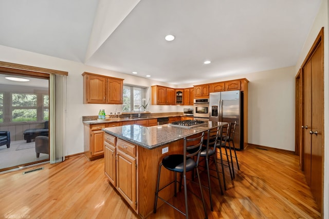 396 Crestwood Rd, Wood Dale, IL 60191 - kitchen featuring stainless steel appliances, a sink, light wood-style flooring, a kitchen island, and a kitchen bar