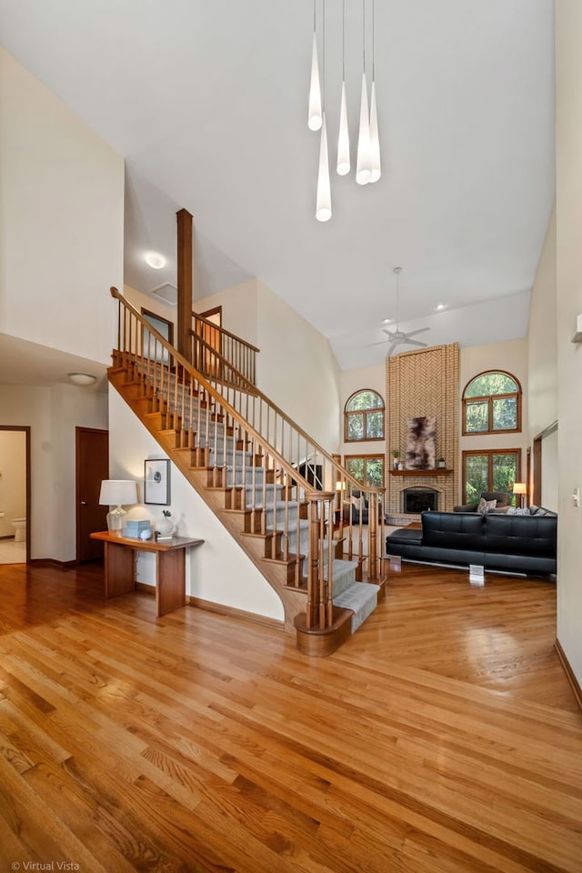 396 Crestwood Rd, Wood Dale, IL 60191 - living room featuring a towering ceiling, stairs, wood finished floors, and a brick fireplace