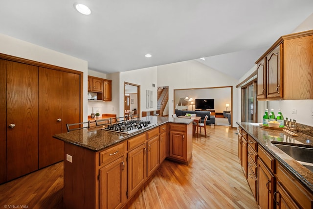 396 Crestwood Rd, Wood Dale, IL 60191 - kitchen featuring stainless steel gas cooktop, a center island, light wood finished floors, vaulted ceiling, and dark stone counters