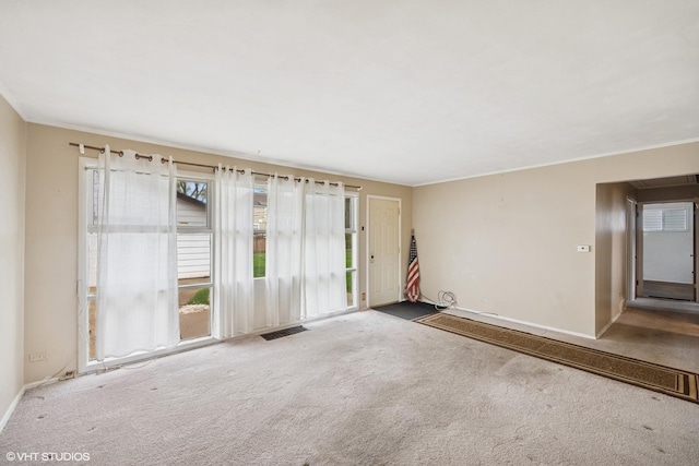 carpeted spare room featuring crown molding and baseboards