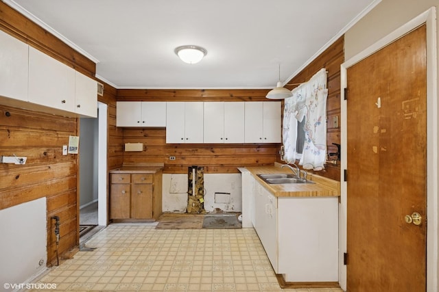 kitchen featuring a sink, light countertops, light floors, white cabinetry, and crown molding