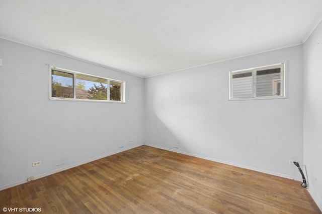 unfurnished room with ornamental molding, wood finished floors, and baseboards