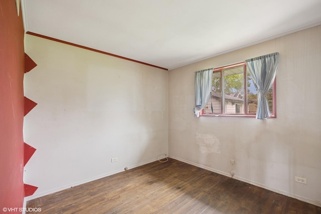 spare room with wood finished floors, baseboards, and ornamental molding