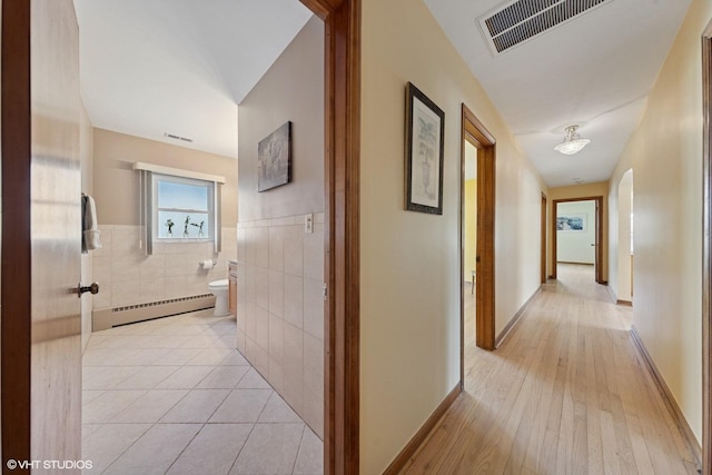 7010 W Devon Ave, Chicago, IL 60631 - hall featuring a baseboard radiator, tile walls, light wood-type flooring, and a wainscoted wall