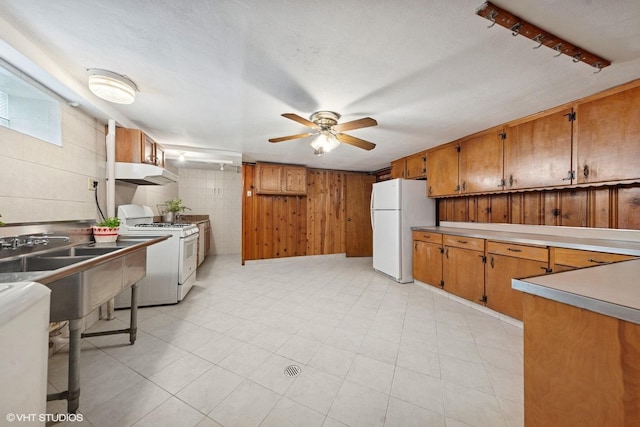 7010 W Devon Ave, Chicago, IL 60631 - kitchen featuring white appliances, under cabinet range hood, ceiling fan, wooden walls, and brown cabinets