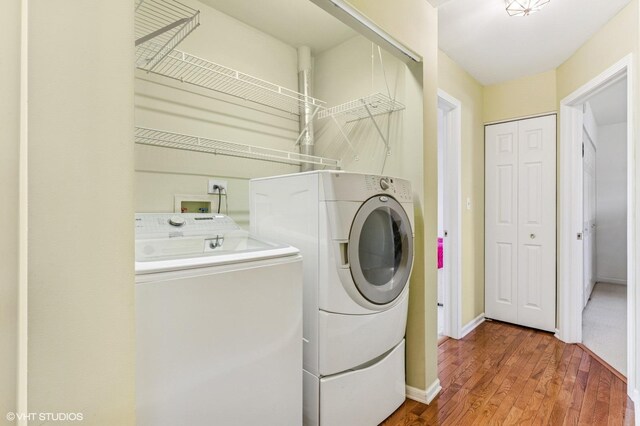 laundry room with washing machine and clothes dryer, baseboards, and wood finished floors