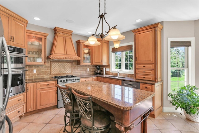 kitchen featuring stainless steel appliances, custom exhaust hood, decorative backsplash, light tile patterned floors, and a kitchen island