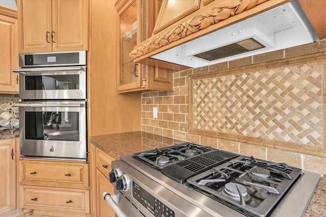 kitchen featuring extractor fan, stainless steel appliances, backsplash, glass insert cabinets, and stone counters