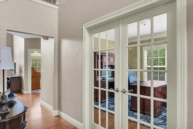 doorway with french doors, baseboards, wood finished floors, and plenty of natural light