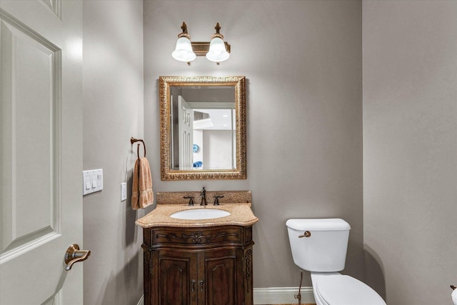 bathroom with toilet, vanity, and baseboards