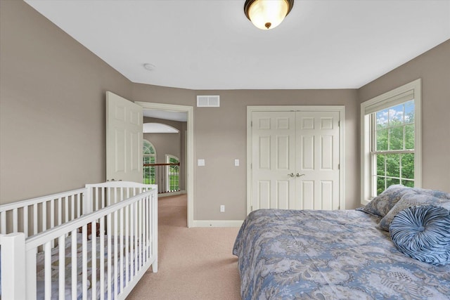 bedroom featuring light carpet, baseboards, and a closet