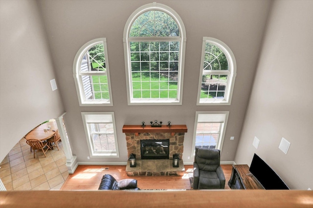 living room featuring a high ceiling, a fireplace, wood finished floors, and baseboards