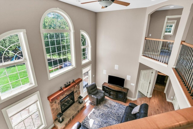 living room with a towering ceiling, plenty of natural light, ceiling fan, and wood finished floors