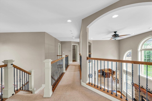 hall with arched walkways, recessed lighting, carpet floors, an upstairs landing, and baseboards