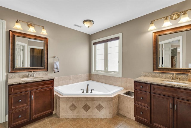 full bath featuring a bath, two vanities, and tile patterned floors