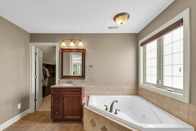 bathroom with a tub with jets, vanity, tile patterned flooring, and baseboards