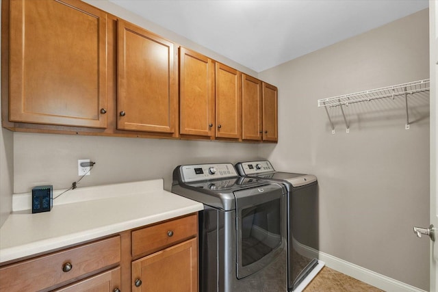 washroom with cabinet space, washer and clothes dryer, baseboards, and light tile patterned flooring