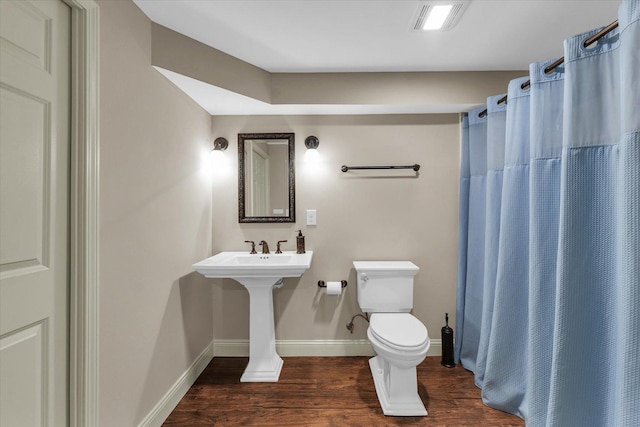 full bathroom with wood finished floors, toilet, baseboards, and curtained shower