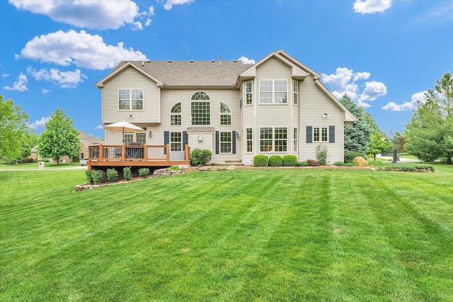 back of property with a deck and a lawn