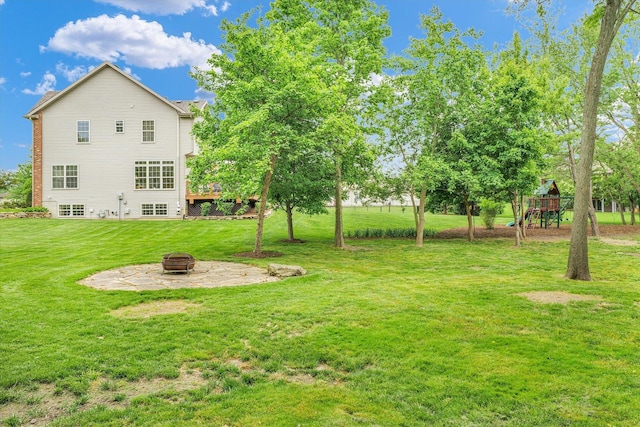 view of grassy yard with a fire pit and a playground