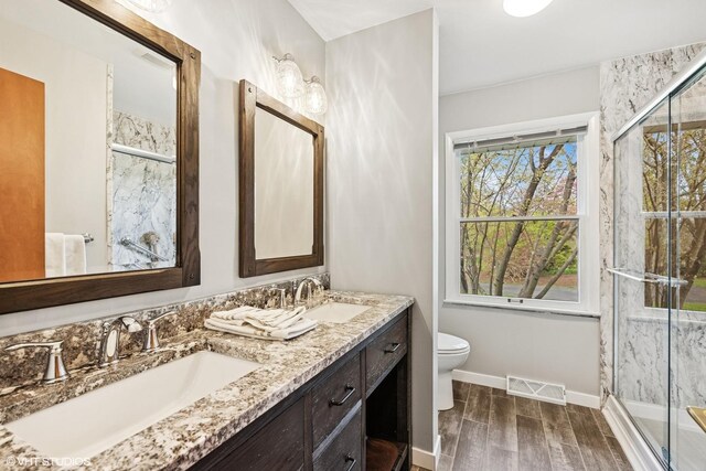 bathroom featuring a sink, a stall shower, wood finished floors, and visible vents