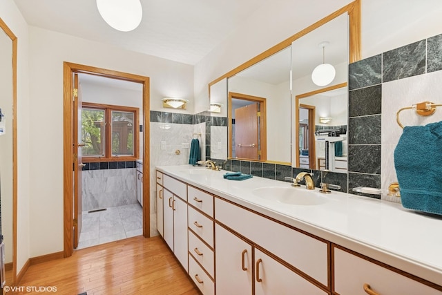 full bath featuring a sink, tile walls, double vanity, and wood finished floors